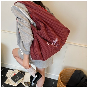 Detailed view of red and white checkered tote bag with white cursive party lettering