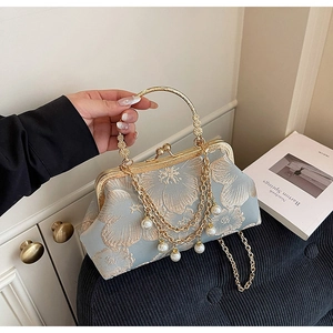 Dettaglio ricamo floreale su borsa da sera in raso blu con frange di catena e perle