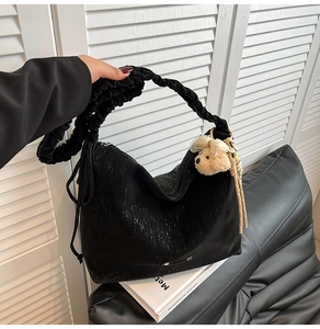 Detail of black tote bag featuring shimmering glitter fabric and ruffled shoulder strap