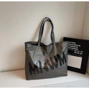 Detail of army green large capacity tote bag with MNWM lettering and dual handle design