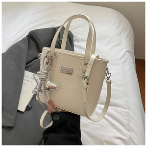 Detail of cream bucket bag with crocodile pattern, star pendant and silver hardware logo