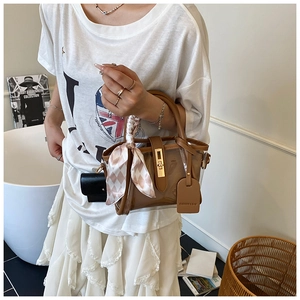 Détail du sac seau en PVC marron avec un foulard en soie décoratif à carreaux rose