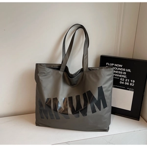 Detail of grey nylon tote bag with black MNWM text on minimalist marble surface