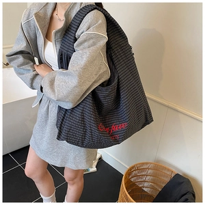 Detail of grid pattern tote bag with red 'Our fave party' embroidery on soft fabric