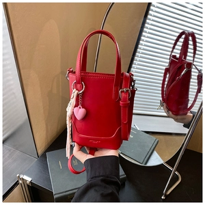 Détail du sac seau rouge avec pendentif cœur rose et accessoire en foulard de soie fleuri