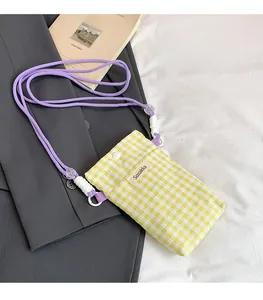 Detail of yellow checkered fabric phone bag with purple rope strap and logo label