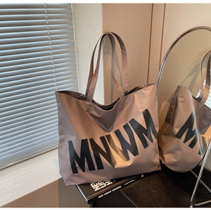 Detail of mauve large capacity tote bag with MNWM lettering and durable fabric