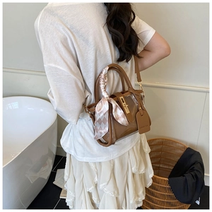 Détail du sac seau en PVC marron avec poignée en foulard et fermoir sur un mannequin