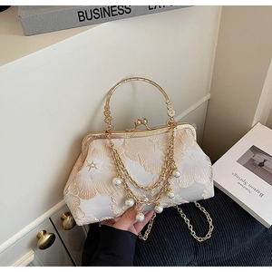 Dettaglio del ricamo floreale su pochette vintage con nappe di perle e cornice