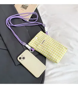 Close-up of yellow checkered canvas phone bag with purple woven strap and snap closure