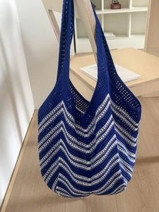 Borsa tote in maglia a righe blu e bianche su una sedia in legno in stile minimal