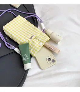 Detail showing internal storage of yellow checkered fabric bag with cosmetics and phone
