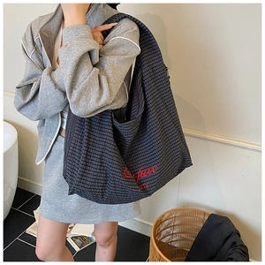 Close-up of a striped tote bag featuring red cursive embroidery and large capacity
