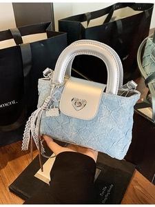 Blue denim bucket bag with silver handles and heart lock shown in a stylish urban setting