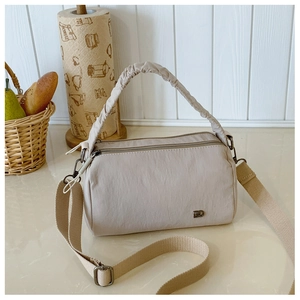 Close-up of beige nylon crossbody bag featuring a ruched handle and metal logo detail
