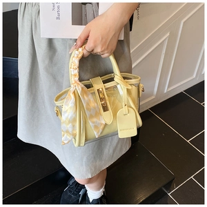 Détail du sac seau en PVC jaune avec poignée en foulard de soie et fermoirs dorés