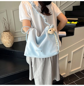 Detail of light blue cloud shoulder bag with pleated strap and plush bear charm