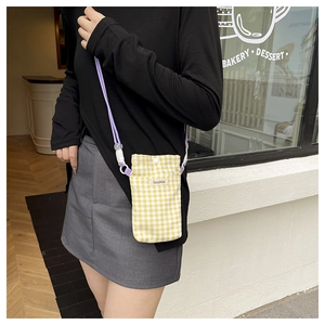 Detailed shot of yellow plaid canvas phone bag with purple strap and Sozakka tag