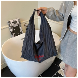 Detail of navy blue plaid tote bag featuring red embroidered letters and zipper closure