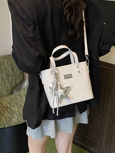 Beige faux crocodile skin bucket bag with star pendant shown in a casual lifestyle setting