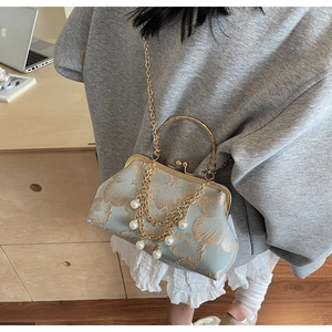 Dettaglio di borsa ricamata vintage con catena di perle e manico dorato elegante