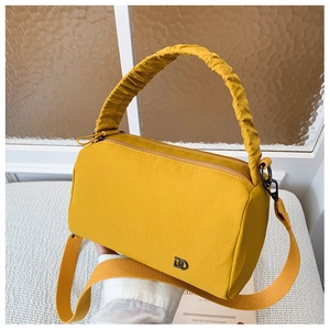Macro shot of yellow pillow crossbody bag featuring scrunchie handle and metal D-logo