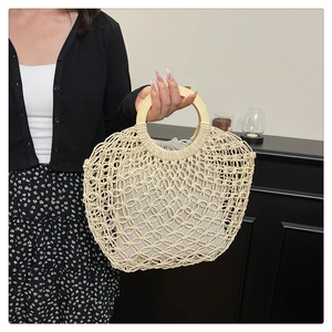 Detail of woven tote bag featuring hollow flower patterns and round wooden handles