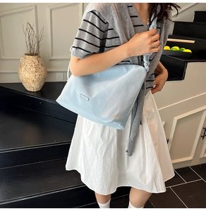 Detail of light blue shoulder bag with pleated cloud strap and silver logo plaque