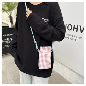 Detail of pink gingham phone bag with adjustable mint green rope strap and woven label