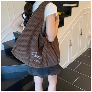 Detail of retro brown checkered tote bag featuring white Outfit Party embroidery