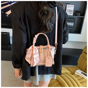 Détail du sac seau rose en PVC transparent avec un foulard à carreaux sur la poignée