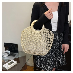 Detail of hollow woven summer bag with round wooden handles and fabric inner lining