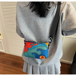 Rear view of a model wearing the colorful abstract art crossbody bag with adjustable strap