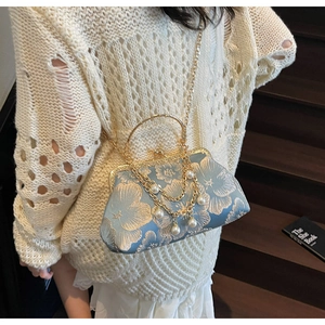 Dettaglio pochette jacquard celeste con ricamo, catena di perle e manico in metallo