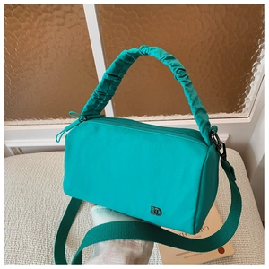Detail of lake blue nylon crossbody bag featuring ruffled cloud handle and woven strap