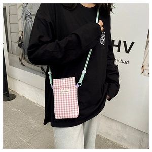 Detail of pink and white checkered canvas phone bag featuring a snap button and woven strap