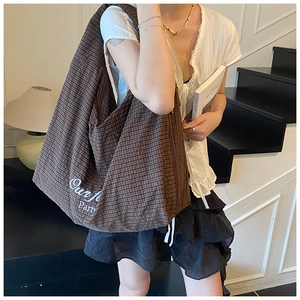 Brown checkered canvas tote bag with lettering shown on model for a retro casual look