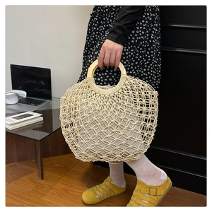 Detail of hollow woven tote bag with round wooden handles and canvas drawstring inner pouch