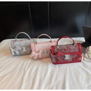Detailed macro view of three textured leather handbags in grey, pink, and red with metal handles