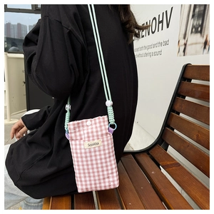 Detailed shot of the pink checkered phone bag with a mint green adjustable strap