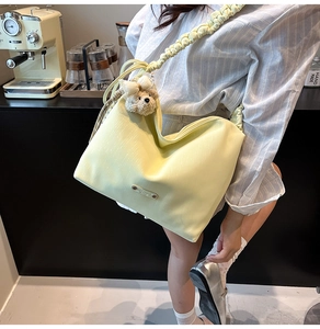 Close-up of yellow shoulder bag with scrunchie strap and cute bear plush charm