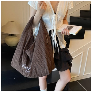 Close-up of brown checkered canvas tote bag with 'Our J Part' embroidery and zip closure