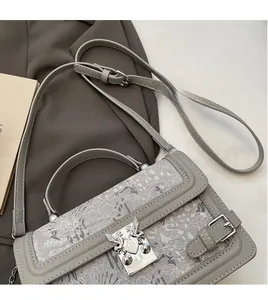 Detail of grey crossbody bag with silver bird-shaped clasp and adjustable long shoulder strap