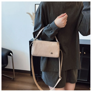Detail showing the ruffled texture and metal logo of the beige crossbody pillow bag