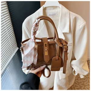 Détail d'un sac seau vintage en cuir marron et PVC avec foulard en soie sur l'anse