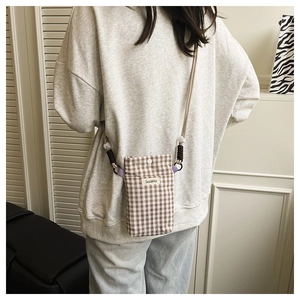 Detailed back view of a brown plaid canvas phone bag with an adjustable beige strap