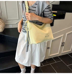 Detail of a creamy yellow tote bag with ruched shoulder straps and side drawstring accents