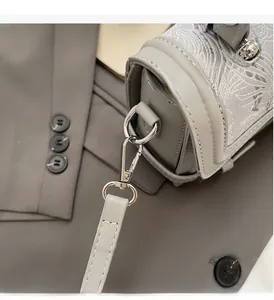 Detailed close-up of grey leather handbag featuring white lace embroidery and silver hardware