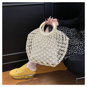 Detail of hollow woven tote bag with wooden handles and matching inner fabric pouch