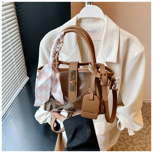 Détail du sac seau vintage en PVC marron avec anse en foulard et boucle dorée